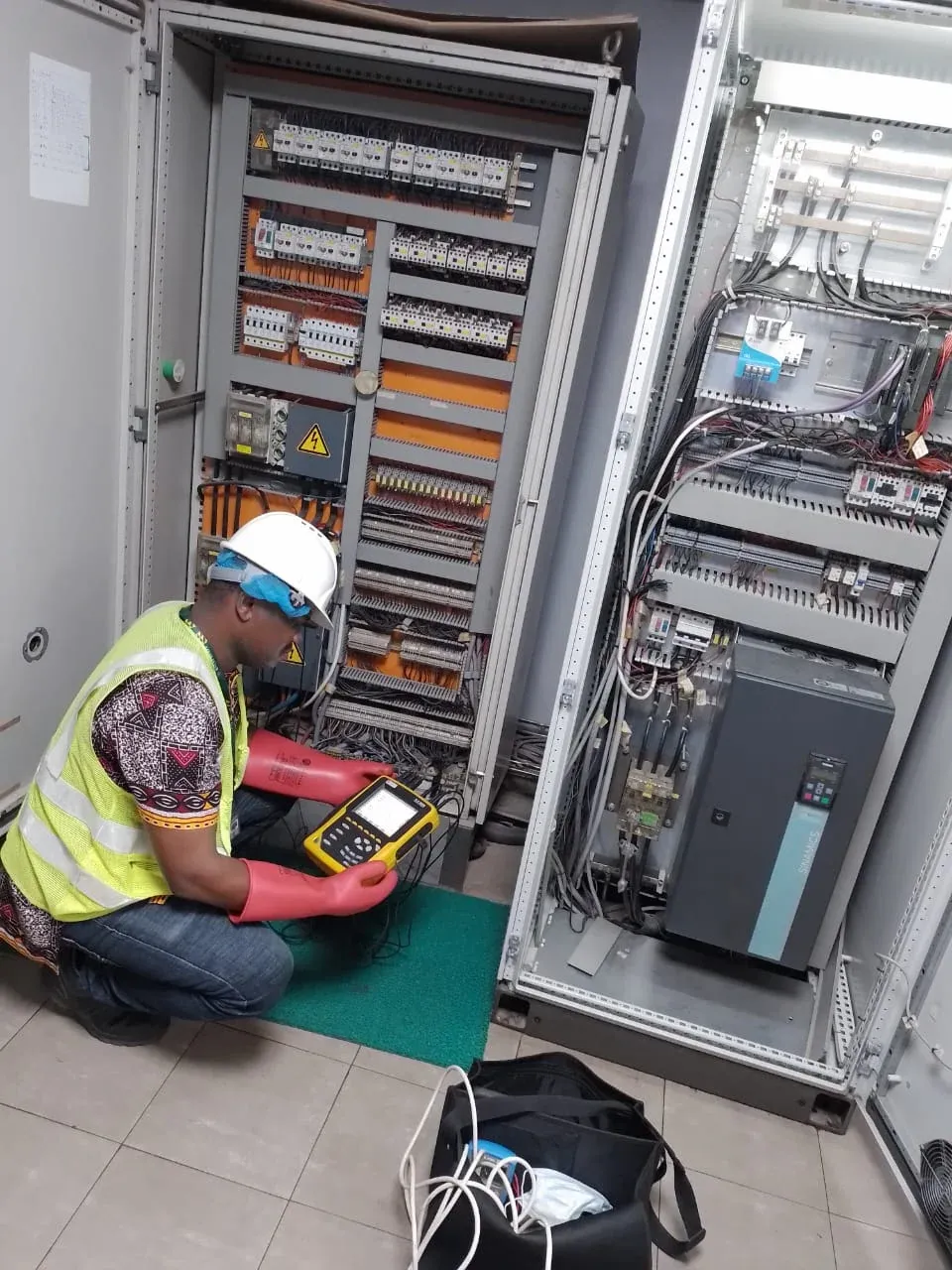 Remotec Ltd engineer in PPE testing a variable-speed drive panel with a power quality analyser
